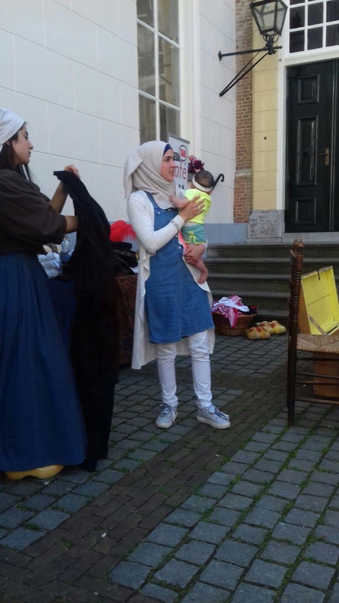 Deelneemster met haar baby op de arm kiest kleding uit bij het bord van het Bredataal Café