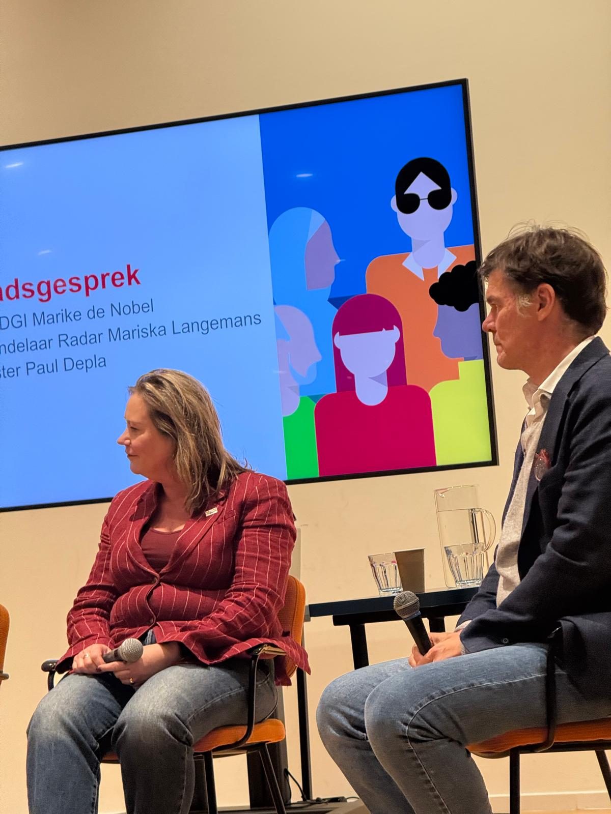 Burgemeester Paul Depla en een panellid in gesprek met de zaal tijdens het Stadsgesprek